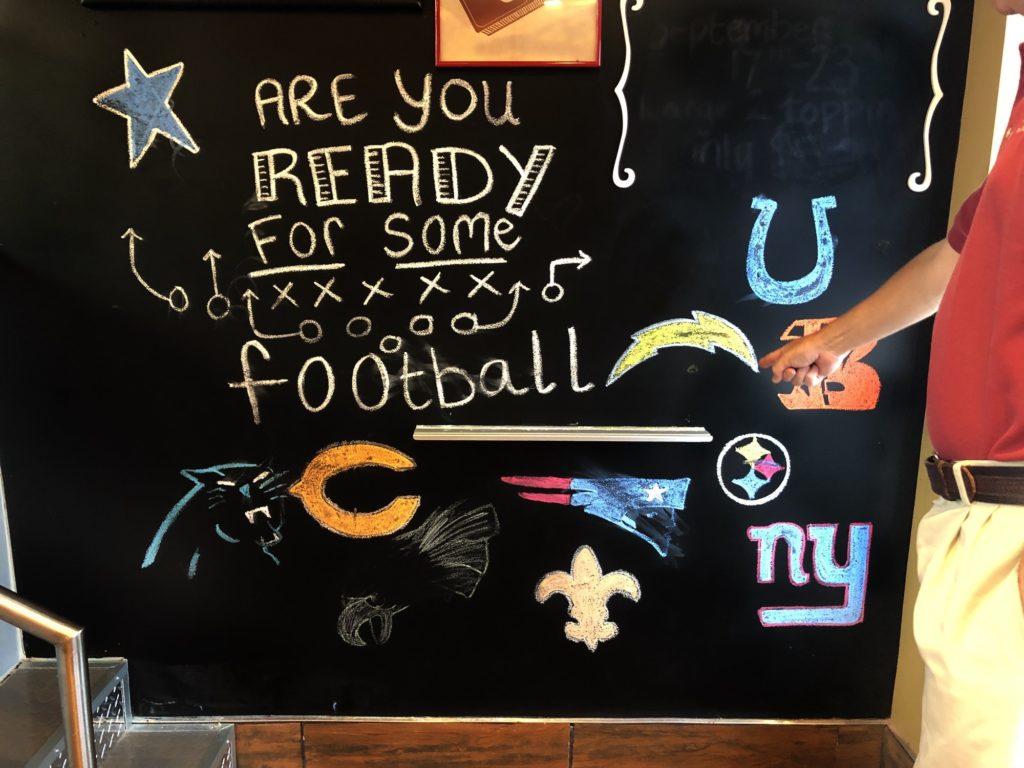 Are you ready for some football text with NFL team logos made with chalk on blackboard at a business